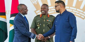 First Officer Haslyn Peters shakes the hand of President Irfaan Ali, as Chief of Staff of the Guyana Defense Force, Brigadier General Godfrey Bess, looks on.