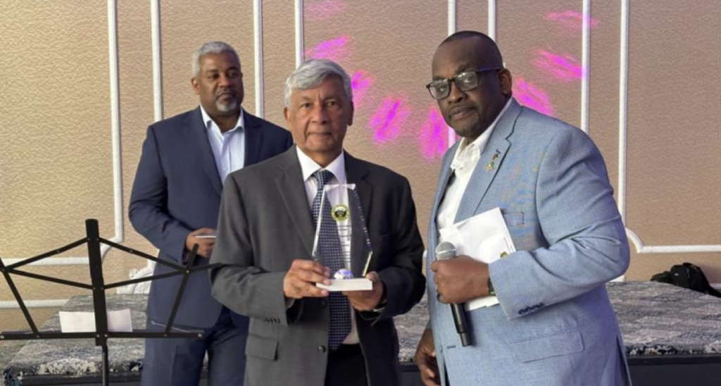 Ashook Ramsaran (center) with award to Dr. David Dabydeen presented by Queens College Alumni Association president John Campbell (right). Event moderator Roberts on the left.