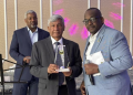 Ashook Ramsaran (center) with award to Dr. David Dabydeen presented by Queens College Alumni Association president John Campbell (right). Event moderator Roberts on the left.