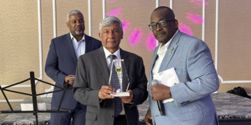 Ashook Ramsaran (center) with award to Dr. David Dabydeen presented by Queens College Alumni Association president John Campbell (right). Event moderator Roberts on the left.